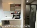 Compact kitchen area with modern cabinets and a view into the adjacent bathroom