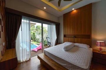 Spacious bedroom with a view of a private pool through sliding glass doors