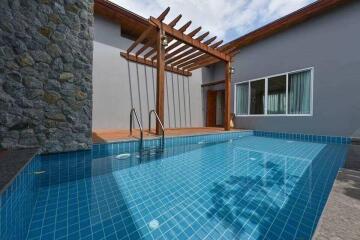 Outdoor pool area with wooden pergola and stone wall accent