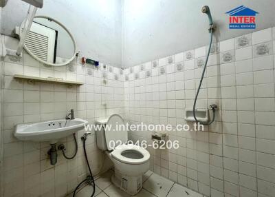 Small bathroom with white tiles, toilet, wall-mounted sink, and shower