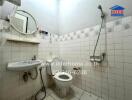 Small bathroom with white tiles, toilet, wall-mounted sink, and shower