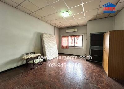 Bedroom with mattress against wall, window with curtains, air conditioner, wardrobe, and tiled floor