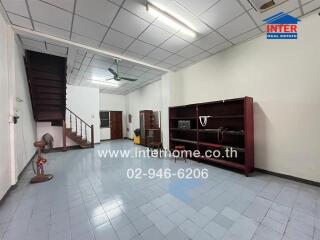 Spacious living room with tiled flooring and wooden staircase