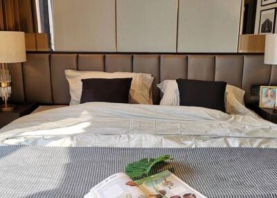 Well-decorated bedroom with a large bed, modern lamps, and reading material