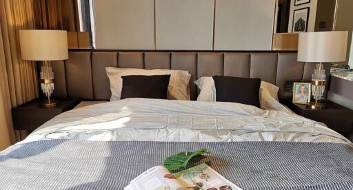 Well-decorated bedroom with a large bed, modern lamps, and reading material