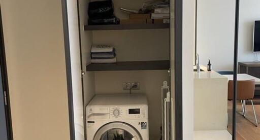 In-unit laundry area with washing machine and storage shelves