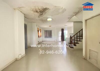 Spacious living area with visible water damage on ceiling