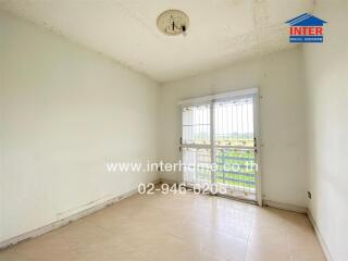 Empty bedroom with large window and tiled floor