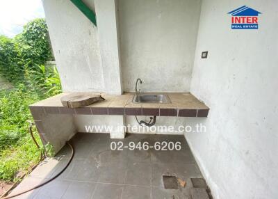 Outdoor kitchen area with sink and tiled countertop