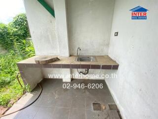 Outdoor kitchen area with sink and tiled countertop