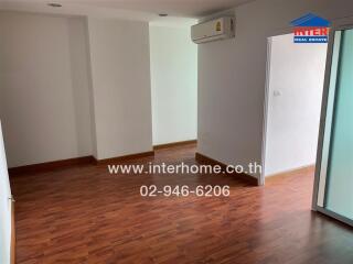 Living room with wooden flooring and wall-mounted AC unit