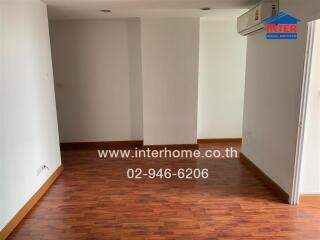 Empty living room with wooden flooring and white walls