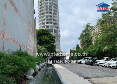 View of a tall modern building with a parking lot and greenery