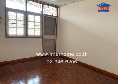 Empty bedroom with wooden floor and barred windows