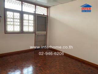 Empty bedroom with wooden floor and barred windows