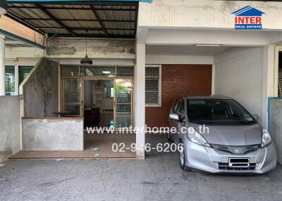 Covered garage with car and entrance to house