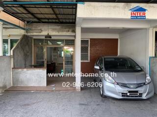 Covered garage with car and entrance to house