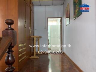 Hallway with wooden furniture and a stair railing beside a doorway