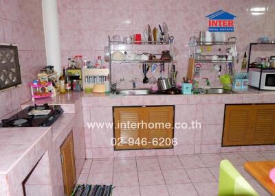 Spacious kitchen with pink tiled walls, countertops, and ample storage