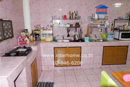 Spacious kitchen with pink tiled walls, countertops, and ample storage