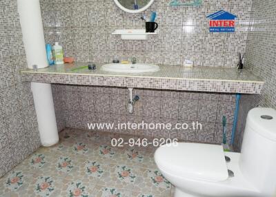 Bathroom with tiled walls and floors, a countertop sink, and a toilet