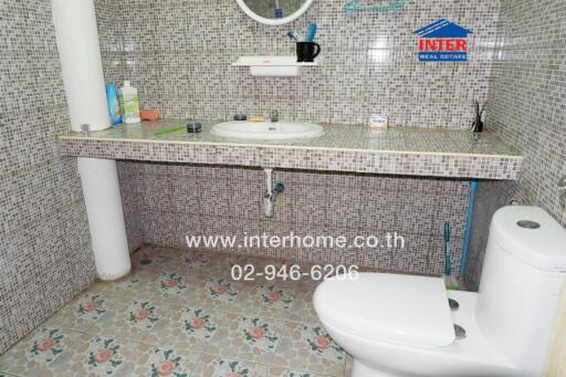 Bathroom with tiled walls and floors, a countertop sink, and a toilet