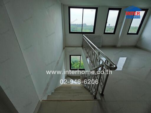 Staircase with metal railing and large windows