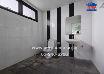 Modern bathroom with white and black tiles, wall-mounted sink, and toilet.