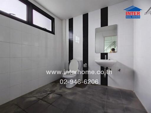 Modern bathroom with white and black tiles, wall-mounted sink, and toilet.