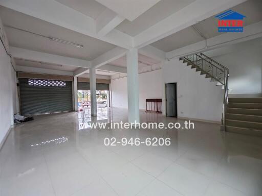 Spacious commercial property with a large open area, stairs, and roll-up doors