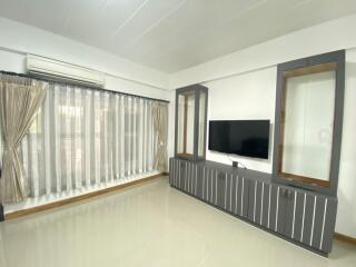 Modern living room with a large window, TV, and air conditioning