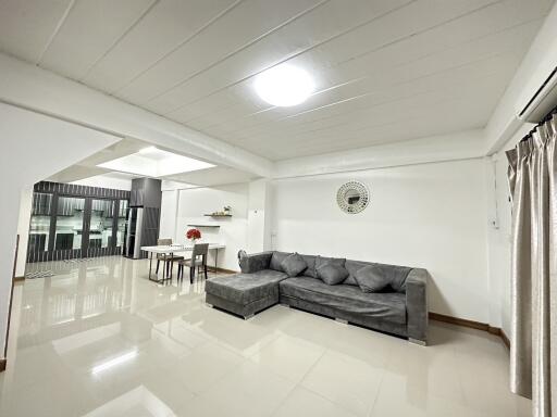 spacious modern living room with grey sofa and view into the kitchen