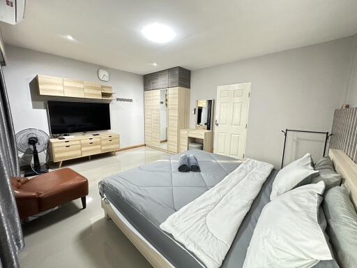 Modern bedroom with king-sized bed, wall-mounted TV, and wardrobe