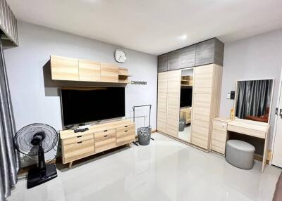 Modern bedroom with wooden furniture, TV, and vanity area