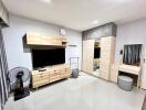 Modern bedroom with wooden furniture, TV, and vanity area