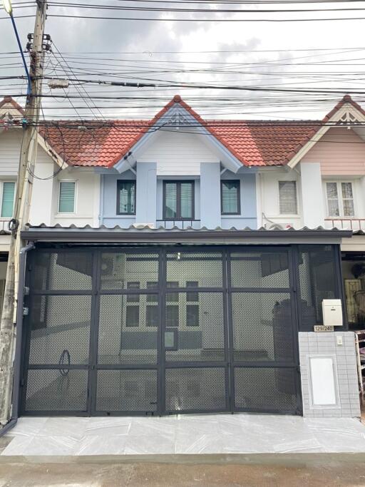 Facade of a residential townhouse with a gated entry and multiple windows