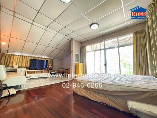 Spacious bedroom with wooden flooring, large windows, and ample natural light