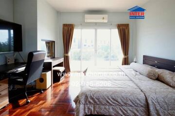 Bright bedroom with a large window, bed, desk, chair, and wooden flooring