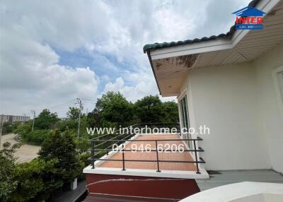 Balcony with a railing and tiled floor, view of trees and cloudy sky