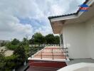 Balcony with a railing and tiled floor, view of trees and cloudy sky