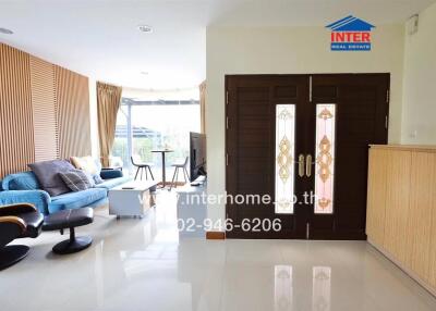 Spacious and well-lit living room with modern furniture, wooden accents, and large windows.