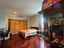 Spacious bedroom with wooden flooring and a bed next to a window with curtains