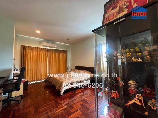 Spacious bedroom with wooden flooring and a bed next to a window with curtains