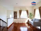 Spacious living room with hardwood floors, large windows and a grey couch