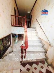 Indoor staircase with wooden railing and patterned wallpaper
