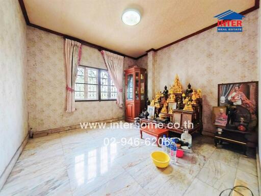 Spacious living room with tiled flooring, a window with curtains, and various decorative items including a wooden display cabinet and a collection of figurines