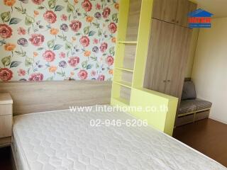 Bedroom with floral wallpaper, wooden furniture, and light-colored mattress