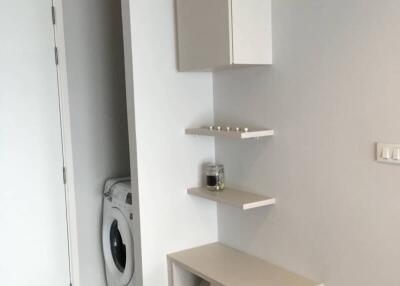 Small laundry area with washing machine, shelves, and cabinets