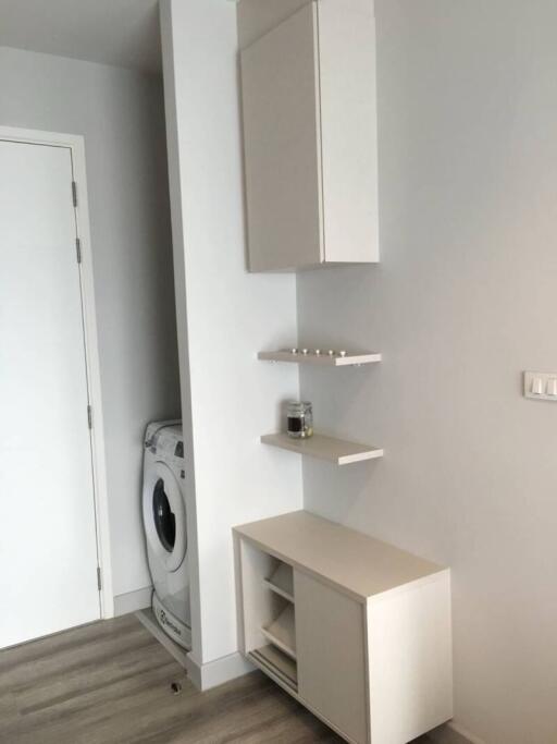 Small laundry area with washing machine, shelves, and cabinets