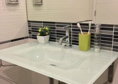 Modern bathroom sink area with tiled backsplash and accessories
